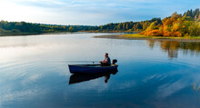  Elderly Man Fishing With A Rod On A Small Fishing Boat On The Lake At Autumn Sunset