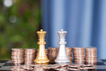 Piles of dollar coins in front of the two queens of both chess players in a duel