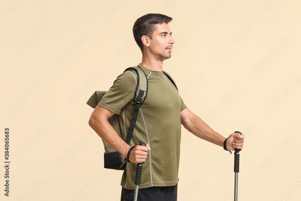 Young man with walking poles on color background