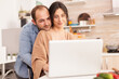 © DC Studio - Smiling couple using laptop in kitchen. Man hugging wife. Happy loving cheerful romantic in love couple at home using modern wifi wireless internet technology