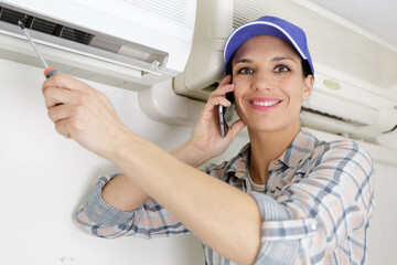 Wall Mural - handywoman on the phone cleaning ventilation system