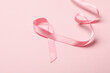 Pink awareness ribbon on pink background, close up