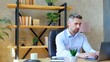 © viacheslav - Confident serious business man manager SEO sits on chair at table in home office works remote distance online uses laptop computer typing on keyboard
