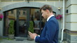 © stockbusters - Thoughtful businessman typing message on mobile phone outdoors.