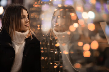 girl christmas lights evening decorated city, a young model on the background of urban decorations and garlands, night city lights