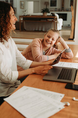 Wall Mural - Woman giving attention to her daughter while working at home