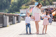 © AnnaDemy - Young cheerful mom with kids on a walk in european city. Kids smiling and having fun. Summer portrait with space for text.