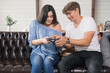 © AnnaDemy - Man teaching his woman how to play games with joystick. Woman smile cheerfully. They relax in cozy home interior.