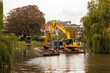 Dreding of inland canals by crane from a pontoon; the dredging spoil is deposited in a barge. Leiden, Netherlands