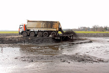 Large Truck With Tipper Trailer Unloads Its Freight Of Dredging Spoil (sludge, Sediment) Into A Storage Compartment (depot)