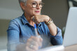 © goodluz - portrait of a beautiful 55 year old woman with white hair working from home