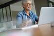 © goodluz - portrait of a beautiful 55 year old woman with white hair working from home