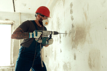 builder with perforator drills holes in concrete wall