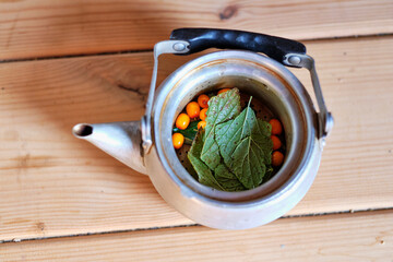 healthy tea in the teapot. Tea with herbs and sea buckthorn. Sea buckthorn drink. Iron teapot