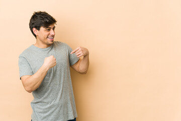 Young cool man surprised pointing with finger, smiling broadly.