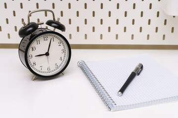 Wall Mural -  notebook with a black alarm clock and a pen on a white background.