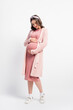 © LIGHTFIELD STUDIOS - full length view of pregnant woman in cardigan and headband touching belly on white