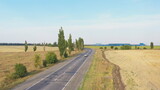 Fototapeta  - Aerial shot of electric car driving on countryside road. New modern vehicle riding fast along highway. Flying over car passing motorway. Traffic in rural environment. Slow motion Back view