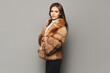© innarevyako - Side view of a model girl in a luxurious fur coat at the grey background. Winter fashion