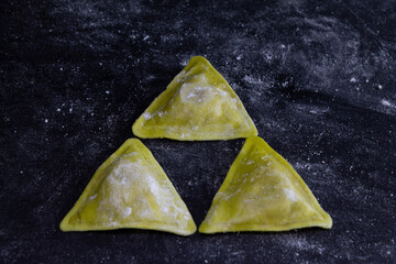 Fresh Triangle Ravioli on floury dark background