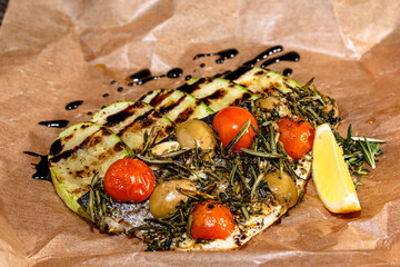 Wall Mural - Baked fish with tomatoes, zucchini and rosemary on paper