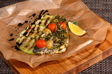 Wall Mural - Baked fish with tomatoes, zucchini and rosemary on paper