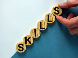 Wood circles with word 'skills' stacking as step stair on paper blue and white background, copy space. Business concept success process.