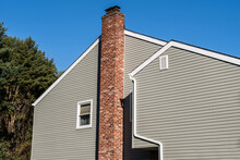 Side Of Older Style White House With Tall Red Brick Chimney Blue