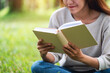 © Farknot Architect - A beautiful young asian woman reading a book while sitting in the park