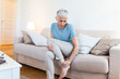© Graphicroyalty - Old age, health problem and people concept - senior woman suffering from pain in leg at home. Senior woman holding her foot with pain.