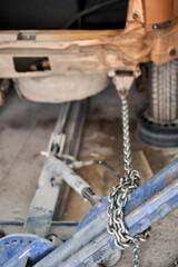 Wall Mural - A broken car with a violation of geometry is on the stocks for leveling. Restoration of vehicles with chain and hook. Repair in the workshop and auto