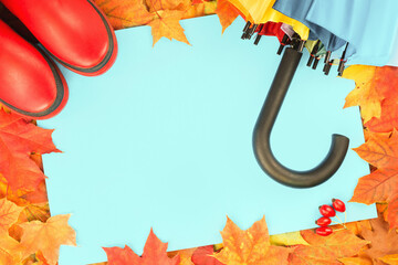 Wall Mural - Autumn leaves frame with red rubber boots and umbrella. Fall foliage banner. Weather forecast, rain. Bright orange and red maple tree leaves. Copy space on blue