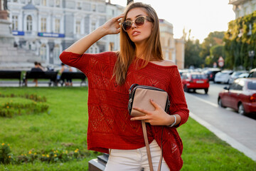 Wall Mural - Elegant blond woman in trendy autumn ourfit posing on the street. Wearing sunglasses, sweater and white jeanse.