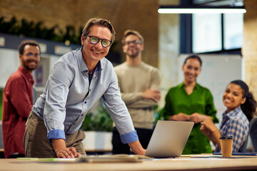 Group of young successful multi ethnic business team looking at camera and smiling while having a meeting in the modern office and coworking space