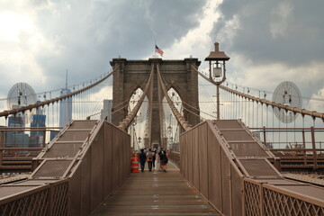 Sticker - Tourists and residents cross Brooklyn Bridge in New York City, New York. Brooklyn Bridge is one of the oldest suspension bridges and was completed in 1883.