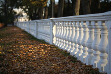 Stone Balustrade Baroque Style In The Design Of The Park.A Row Of Columns Extending Into The Distance Against The Background Of Fallen Leaves.Autumn Landscape.The Background Is Blurred.