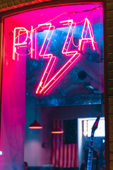 neon pizza inscription on the window of the pizzeria at night glows advertisement