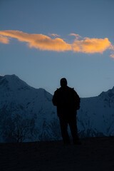 Wall Mural - silhouette picture of a man with snow capped mountains in background 