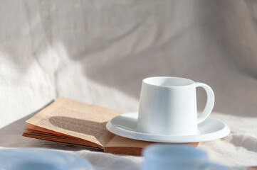 A casual holiday with hot coffee in a white coffee mug put on the book with the warm morning sunshine from the window to feel relaxed good for relaxing