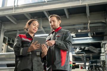 Poster - Two young quality control managers of polymer processing factory using tablet