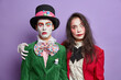 © wayhome.studio  - Two friends dressed in halloween carnival costumes embrace and have friendly relationships wear spooky makeup celebrate holidays isolated on purple background. Scared hatter poses with female zombie