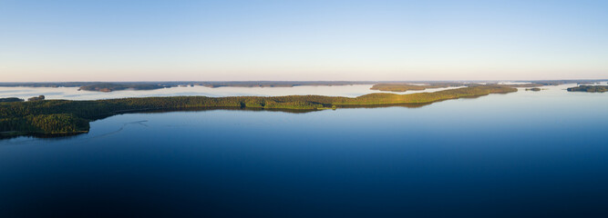 Wall Mural - Panoramic view of sunset over the lake in nation park. Amazing landscape of Paijanne lake with crystal clear water and Perfect blue sky. Drone shot.