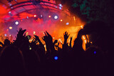 Abstract blur atmosphere: happy people enjoying outdoor music festival concert, raised up hands and clapping of pleasure, active night life concept, play of light and shadow on the stage