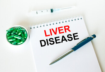 Text Liver Disease written in a notebook with a blue pen and a bunch of pills