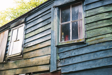 window of an old boat house with rotten wood and different green paint