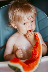 Wall Mural - Happy toddler boy eating watermelon in his highchair