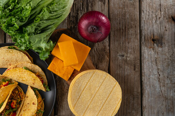 Wall Mural - Corn tortillas for mexican tacos on rustic wooden background. Backstage of preparing traditional tasty tacos. Concept of street food. Horizontal format.