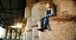 © VAKSMANV - Pretty nice small Caucasian blonde girl smiling, resting and sitting on hay stocks in barn in August. Summer childhood in countryside. Little beautiful kid spending time in shed at farm. Happy child.
