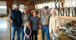 © VAKSMANV - Portrait of happy Caucasian family of three generations standing in shed with livestock and smiling. Old parents with children and grandchildren in stable. farmers at farm. Indoor. Sheep on background