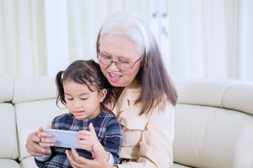 Poster - Old woman with her grandchild using a mobile phone